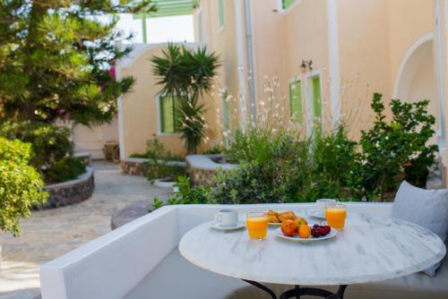 a table with a plate of fruit and two glasses of orange juice at Joanna Villas in Kamari