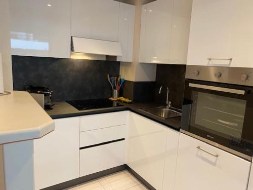 une cuisine avec des armoires blanches et un four à plaques de cuisson dans l'établissement Chez Babette, à Cannes