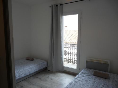 um quarto com uma cama e uma grande janela em Joli appartement quartier Brassens 55 m2 à 2 mn du centre ville em Sète