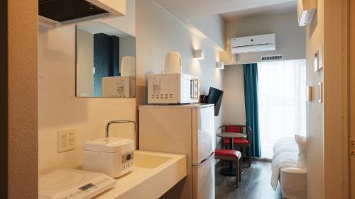 a room with a kitchen with a sink and a refrigerator at New Normal Condo in NAHA AIRPORT ニューノーマルコンドイン那覇エアポート in Naha