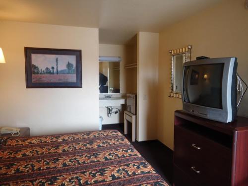 a hotel room with a bed and a tv at Economy Inn in Victorville