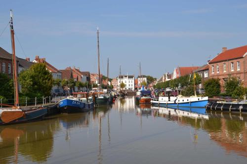 un groupe de bateaux amarrés dans un canal avec des maisons dans l'établissement Ferienwohnung Hafensicht 25507, à Weener