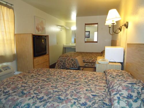 a hotel room with two beds and a television at Economy Inn in Victorville