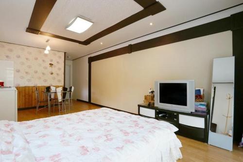 a bedroom with a bed and a tv on a wall at Blue Sky Milky Way Pension in Yangyang