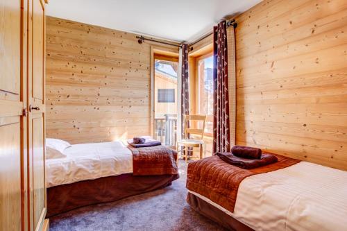 deux lits dans une chambre aux murs en bois dans l'établissement Le Mélèze, à Morzine