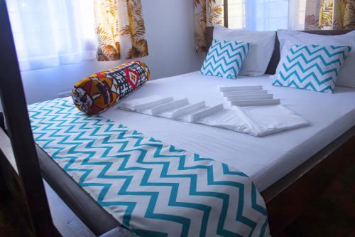 Bett in einem Zimmer mit einer weißen Matratze und Kissen in der Unterkunft Cycad Palm Diani in Diani Beach