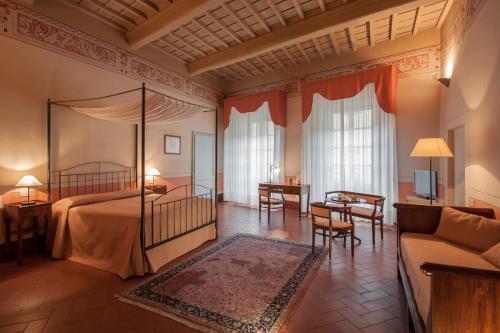 a bedroom with a bed and a table and a couch at Hotel L'Antico Pozzo in San Gimignano