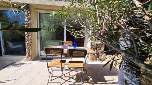 une table avec trois chaises et un vase bleu sur elle dans l'établissement La Petite Villa 2 personnes, à Porto-Vecchio