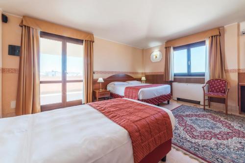 um quarto de hotel com duas camas e uma varanda em Hotel Riviera Fiumicino em Fiumicino