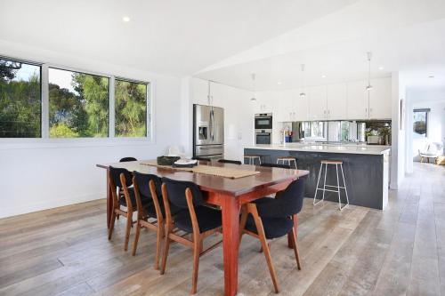 a kitchen and dining room with a wooden table and chairs at Oceanside I Pet Friendly Absolute Beachfront in Culburra Beach