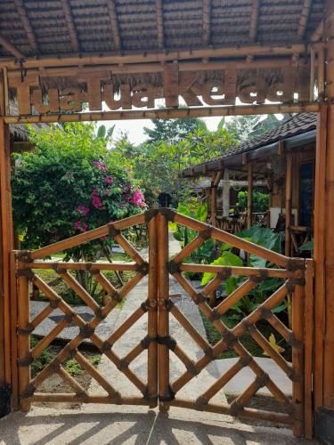 a wooden gate leading into a garden with flowers at Tua Tua Keladi Bungalows in Gili Islands