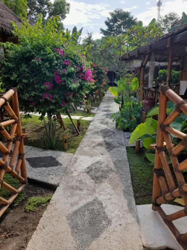 a walkway in a garden with flowers and trees at Tua Tua Keladi Bungalows in Gili Air