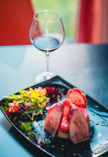 a plate of food next to a glass of wine at Drina Hotel in Bijeljina