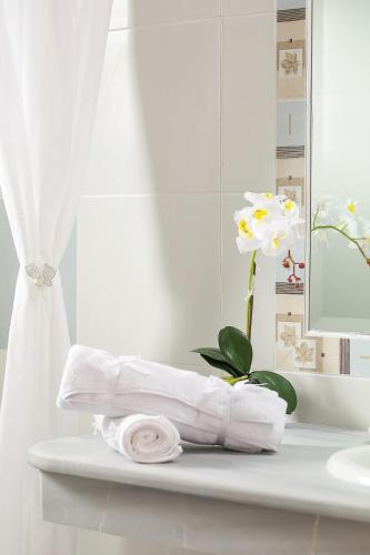 a pile of towels on a bathroom counter with a flower at Dreamy Apartments Corfu in Kontokali