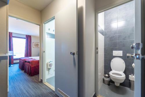 łazienka z toaletą oraz pokój z łóżkiem w obiekcie Hotel Ambiotel w mieście Tongeren