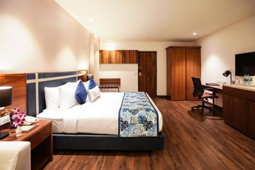a hotel room with a bed and a desk at Regenta Suites Gurugram, Sector 49 Sohna Road in Gurgaon