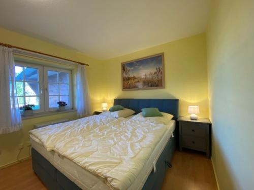a bedroom with a large bed and two windows at Hus op de Wurth Nr 7 in Büsumer Deichhausen