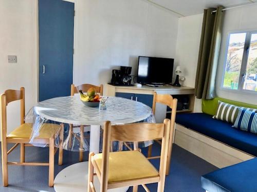 a dining room with a table and chairs and a couch at Mobil Home - 4 personnes in Saint-Martin-Plage