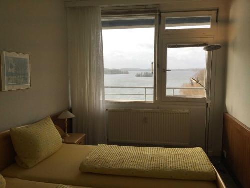 a bedroom with a bed and a large window at App_ an der Seepromenade _ Mittels in Malente