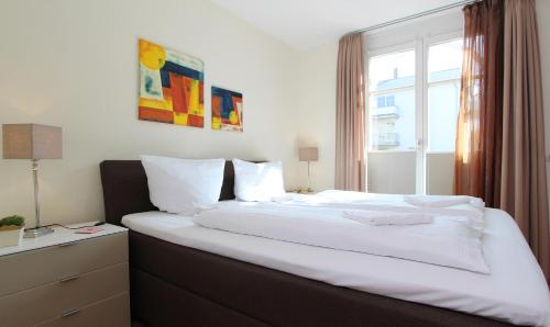 a bedroom with a large white bed with a window at Ferienwohnung Waldblick Nr. 11 in Kühlungsborn