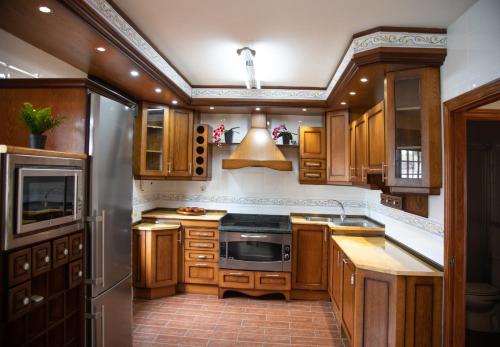 a kitchen with wooden cabinets and a stove top oven at TOLEDO ENCANTADO Piscina y BBQ privada 2,5 km de Puy du Foy in Argés