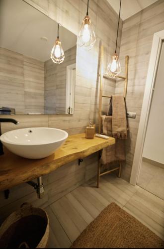 a bathroom with a sink and a mirror and lights at L'Hortet del iaio in Camarles