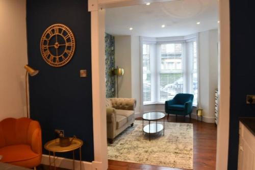 a living room with a clock on the wall at The Cheltenham, stylish 1-bed Victorian apartment in Harrogate