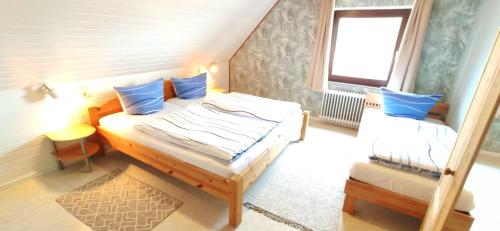 ein Schlafzimmer mit einem Bett mit blauen Kissen und einem Fenster in der Unterkunft Gästehaus Zur alten Post Wohnung Ost in Dornum