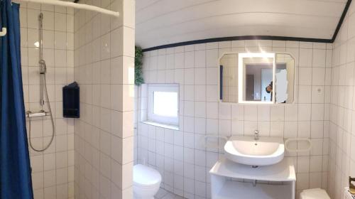 ein Badezimmer mit einem Waschbecken, einem WC und einem Spiegel in der Unterkunft Gästehaus Zur alten Post - Landhaus EG in Dornum