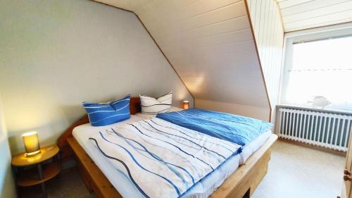 Schlafzimmer mit einem Bett mit blauen und weißen Kissen in der Unterkunft Gästehaus Zur alten Post - Wohnung Nord in Dornum