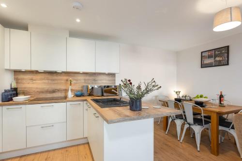 a kitchen with white cabinets and a table with chairs at Host & Stay - Farrier William in Margate
