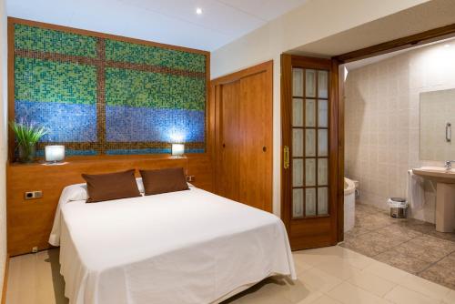 a bedroom with a white bed and a bathroom at Hotel Capri in Tossa de Mar