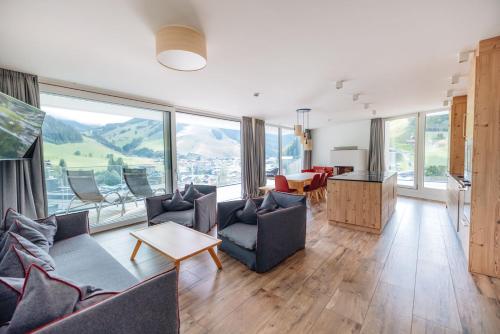 ein Wohnzimmer mit Sofas, einem Tisch und Fenstern in der Unterkunft Adler Resort in Saalbach-Hinterglemm