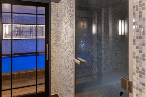 baño con puerta de cristal que conduce a la piscina en Les Matins de Paris & Spa, en París
