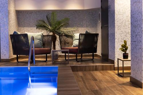 - un hall avec deux chaises et une piscine dans l'établissement Les Matins de Paris & Spa, à Paris