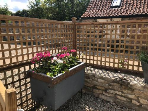 a wooden fence with a planter with flowers in it at STABLES Stylish comfortable peaceful cottage with parking and outdoor space in Holt