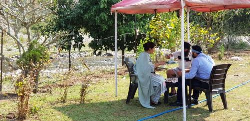 a group of people sitting at a table under an umbrella at The Raajas - Camp & Resorts in Rishīkesh