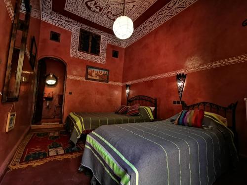 a bedroom with two beds in a room with red walls at La Petite Kasbah in Zagora