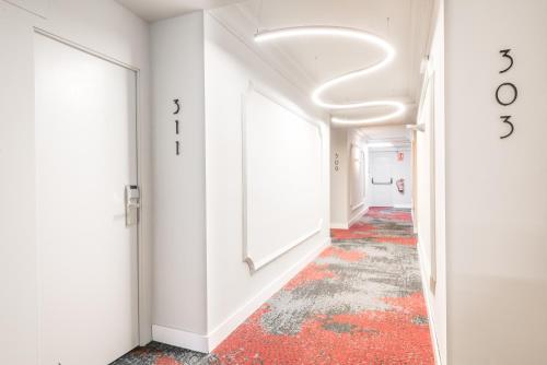 萊里達的住宿－三思公園酒店，走廊上设有白色的墙壁和红色的地板