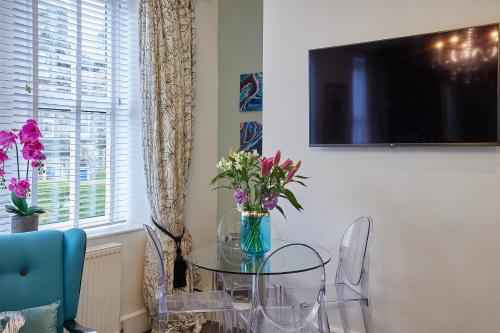 a dining room with a glass table with flowers on it at The Granville - Delightful 2-bed Victorian Apartment in Harrogate