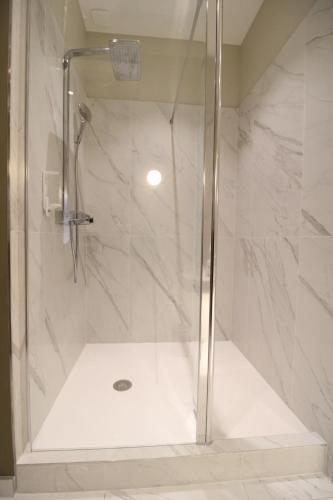 a shower with a glass door in a bathroom at MiHotel Sala in Lyon