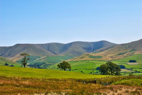 a green pasture with mountains in the background at Lune Cottage nestled between Lake District and Yorkshire Dales in Tebay