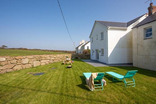 a yard with two chairs and a stone wall at Cynibre in Penzance