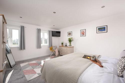 a white bedroom with a bed and a tv at Cynibre in Penzance