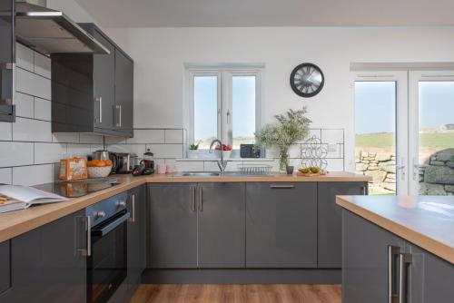 a kitchen with gray cabinets and a clock on the wall at Cynibre in Penzance
