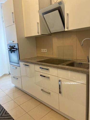 a white kitchen with a sink and a microwave at Apartment KLASSIKO in Bremerhaven