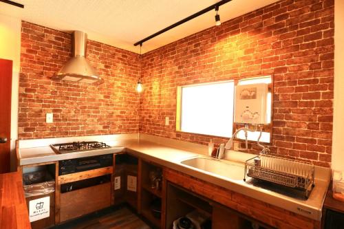 a kitchen with a sink and a brick wall at Guesthouse Bontea - Vacation STAY 54022v in Kamakura