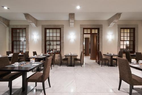 a dining room with tables and chairs and windows at Eurostars das Artes in Porto