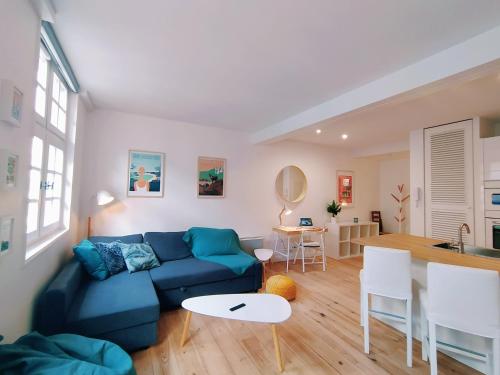 un salon avec un canapé bleu et une cuisine dans l'établissement Nikki’s House, à Bayonne