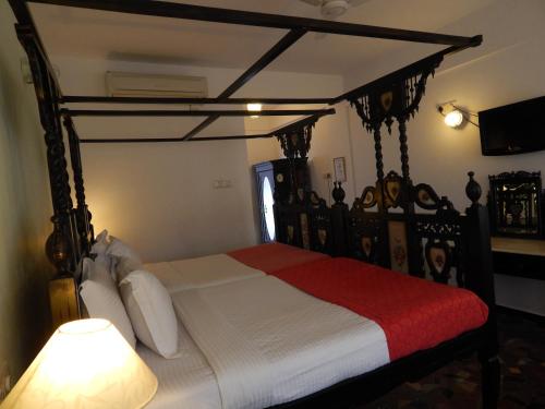 a bedroom with a canopy bed with a red blanket at WelcomHeritage Panjim Inn in Panaji
